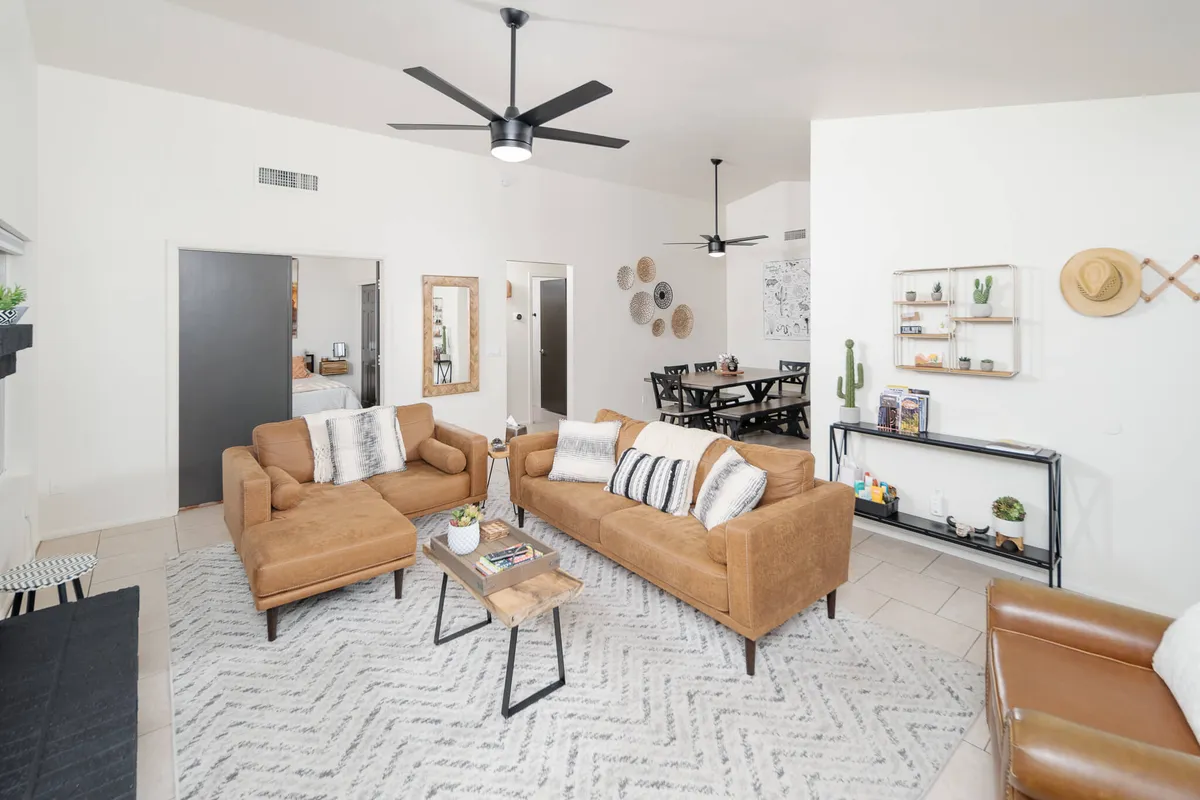 A view of a living area featuring brown sofas, a wooden coffee table, and decorative shelving. The layout is open and welcoming, hinting at a seamless flow between spaces and offering a relaxed setting for socializing and entertainment.