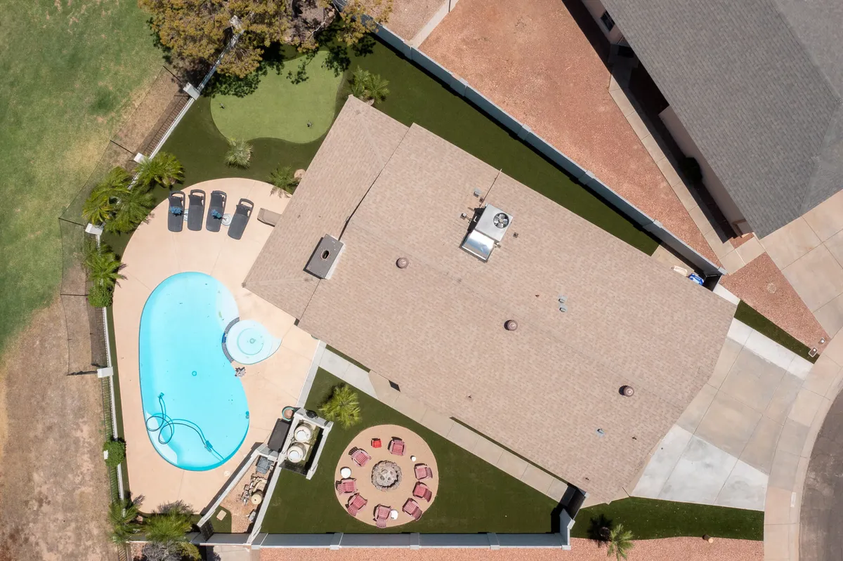 This image captures the backyard featuring a swimming pool, outdoor seating area, and a landscaped lawn. It's set up for relaxation and social gatherings, with the sun setting and casting a golden glow over the space.