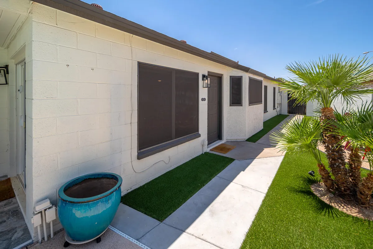 The front exterior of the home with a welcoming entrance shaded by a palm tree and accented with a vibrant blue planter. The approachable entryway hints at the privacy and security of the residential neighborhood.