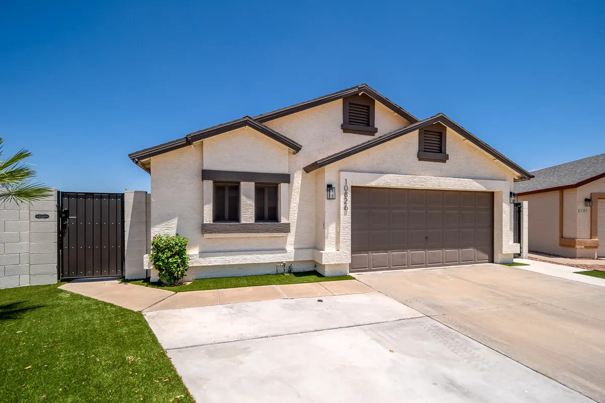This image shows the front door and garage of the property with a landscaped lawn, evoking a welcoming atmosphere. The setting sun casts warm light, suggesting the anticipation of returning home after a day out at the ballpark or local entertainment venues.