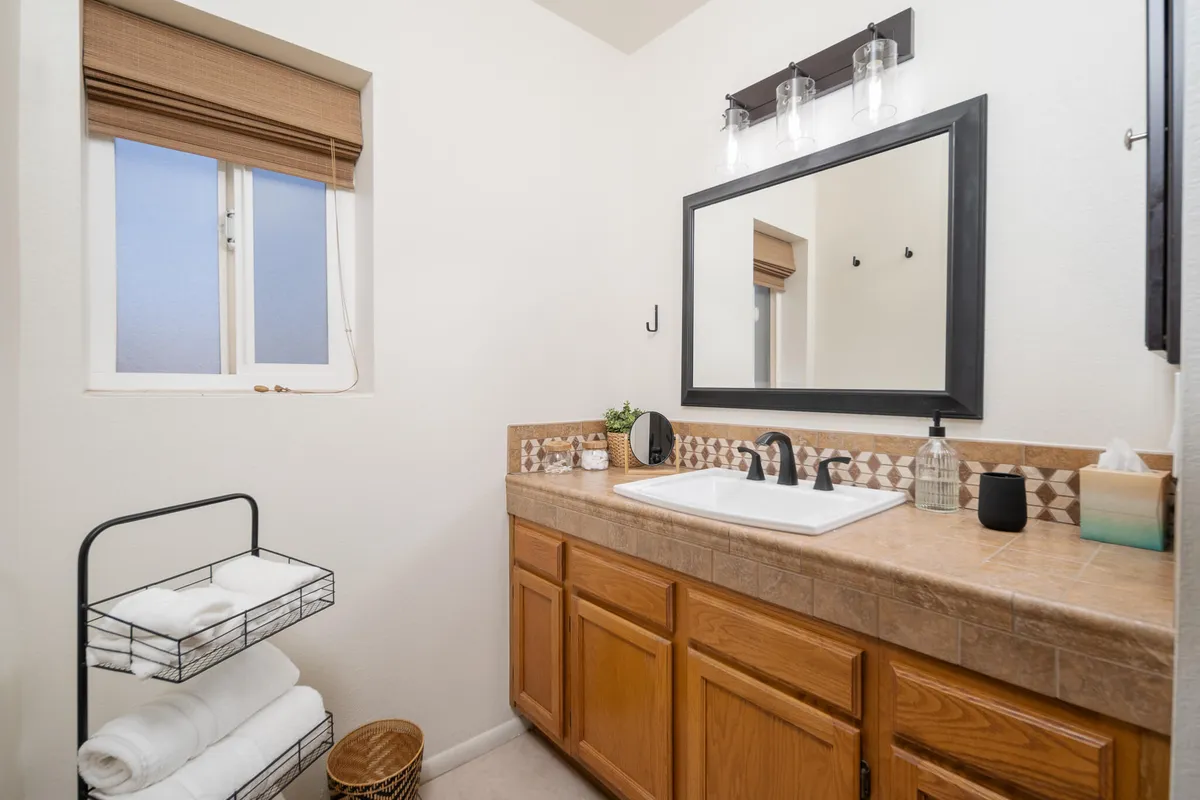 A tranquil bathroom scene with a sleek sink, a large framed mirror, a vanity, and neatly folded towels. The mood is calm and inviting, making it easy to picture refreshing morning or relaxing evening routines.